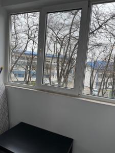 Tres ventanas en una habitación con vistas a los árboles. en Park Lake Mall Studio, en Bucarest