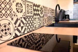 a kitchen with black and white tile on the wall at Maison Super Calme et Confortable - Idéalement Située - Clim - Vue Montagnes - Piscine Partagée - Parking Gratuit - Lou Tranquillou in Sauzet