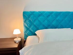 a bed with a blue headboard and a lamp on a table at Nicer Family in Leshan