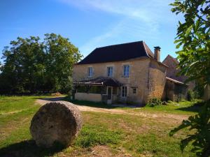 an old house with a large rock in front of it at Charme et tranquillité au cœur du Périgord in La Rafigne