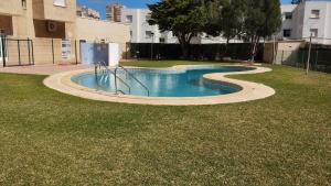 a swimming pool with a slide in the grass at El buen sol de la manga in La Manga del Mar Menor