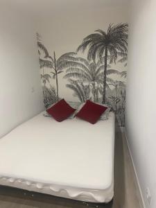 a bed with two red pillows in a room at Petit nid au centre historique de Marvejols in Marvejols