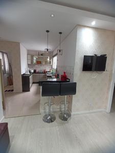 a kitchen and living room with a bar stool in it at Apartamento completo 2 quartos a 3km basílica in Aparecida