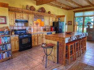 a kitchen with wooden cabinets and a island with a stove at Mountain View Room & Bath in Crestone