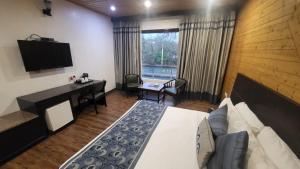 a bedroom with a bed and a desk and a television at Comfort Inn Coral River Resort in Pathānkot