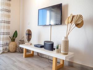 a living room with a table with a tv on a wall at Boho house, Albufeira in Albufeira