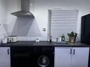 a kitchen with a sink and a washing machine at Modern 3-Bedroom Home with Cozy Cinema-Style Living Space in Cumbernauld +9 photos