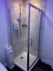 a shower with a glass door in a bathroom at Modern 3-Bedroom Home with Cozy Cinema-Style Living Space in Cumbernauld