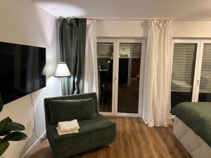 a bedroom with a green chair and a bed at Fächerlofts Black Forest Terrasse 40qm Studio WLAN - Messe Karlsruhe in Durmersheim