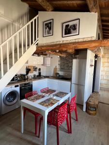 a kitchen with a white table and red chairs at Lou Mirèio in Aigues-Mortes