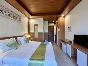 a bedroom with a large bed and a flat screen tv at Anindya Sanur in Sanur