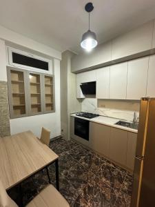 a kitchen with white cabinets and a wooden table at Kvartira in Tbilisi City