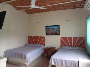 a bedroom with two beds and a ceiling at Casa Regina in Rincon de Guayabitos