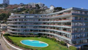 un grand bâtiment avec une piscine devant dans l'établissement Departamento en Reñaca Vista al Mar, à Viña del Mar