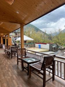 a porch with wooden chairs and a table with a view at Brahma Cottages in Kasol