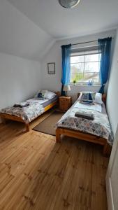 a bedroom with two beds and a window with blue curtains at Dom u Kapitana w Lubiatowie in Lubiatowo