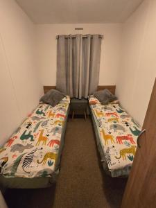 two beds in a small room with a curtain at B17 Sunnymede Caravan Park, Fantasy Island, Ingoldmells in Ingoldmells