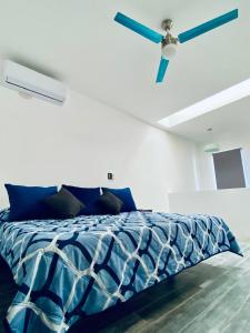 a white bedroom with a blue bed with a ceiling fan at Departamento Arrecife in La Paz +8 photos