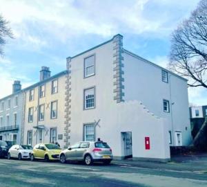 Un edificio blanco con coches aparcados delante. en The Luxury Dartmoor Den, Dartmoor, Devon, en Ashburton