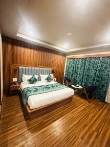 Un dormitorio con una cama grande y suelos de madera. en Shahi Group of Hotels Srinagar, en Srinagar