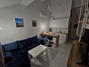 a living room with a blue couch and a kitchen at Apartamenty nad Kamiennym Potokiem 2 in Szczytna