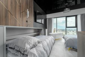 a bedroom with two beds and a tub and a window at Hanza Tower Sky Lux 17th floor in Szczecin +30 photos