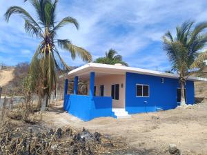 a blue house on the beach with palm trees at Casa paraiso in Maito