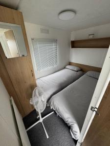 a small bedroom with two beds and a fan at Seawick Holiday Park Caravan Hire in Saint Osyth +8 photos