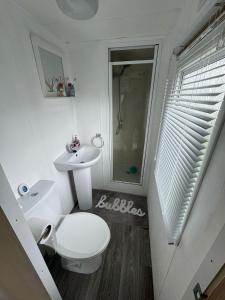 a white bathroom with a toilet and a sink at Seawick Holiday Park Caravan Hire in Saint Osyth