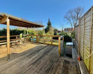 ヘンドンにあるCharming 2 bedroom with a huge Gardenの木製デッキ(テーブル、椅子付)