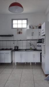 a large kitchen with white cabinets and a window at casa da meg in Tiradentes