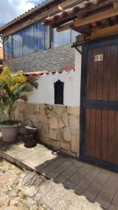 a house with a wooden door and a stone wall at casa da meg in Tiradentes