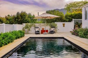 a swimming pool in a yard with an umbrella at The Hedge Cottage in Riebeek-Kasteel