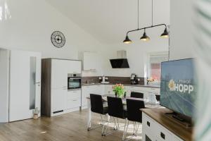 une cuisine avec des armoires blanches et une table avec des chaises dans l'établissement Ferienhaus Dorfkiek - Bauernhof Hopp Vadersdorf, à Fehmarn
