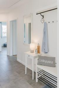 Cette chambre blanche dispose d'une table et d'un miroir. dans l'établissement Ferienhaus Dorfkiek - Bauernhof Hopp Vadersdorf, à Fehmarn 56 autres photos