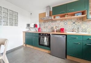 a kitchen with green cabinets and a stove top oven at T2 Au Calme Avec Jardin in Beaune +25 photos