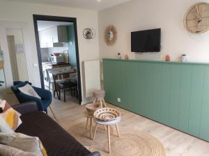 salon z kanapą i zieloną ścianą w obiekcie Charmant logement Guidel Plage, chambre vue mer, piscine chauffée w mieście Guidel