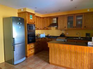 a kitchen with wooden cabinets and a stainless steel refrigerator at Monte Açores in Ferreira do Alentejo