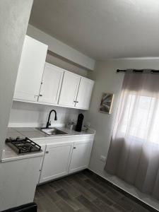 a kitchen with white cabinets and a sink and a window at Hotel Mision Ferrer in San Vicente
