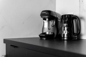 a black counter top with affeepot and a coffee maker at Hanza Tower Sky Lux 17th floor in Szczecin
