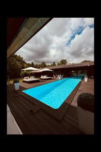 a large blue swimming pool with a wooden deck at Villa des châteaux du Pessac leognan in Martillac +16 photos