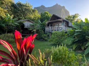 a house with a balcony with a mountain in the background at Landing One Lodge in Bora Bora