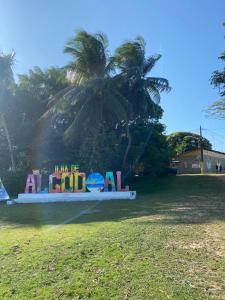 a sign in a park with a palm tree in the background at Pousada Luz do Sol in Algodoal