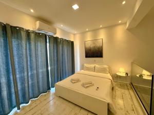 リマソールにある1-bedroom duplex 100m by the seaのベッドルーム(白いベッド、青いカーテン付)