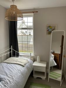 ein Schlafzimmer mit einem Bett, einem Spiegel und einem Fenster in der Unterkunft Victorian Woodbridge cottage in Melton
