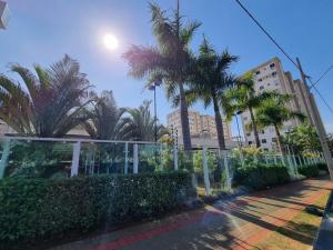 a street with palm trees and a fence at Apto 400m UEL, 2 quartos, ar condicionado egaragem in Londrina