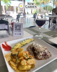 a plate of food and a glass of wine on a table at New Garden Hotel in Sosúa +26 photos