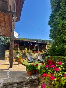 a garden with flowers and chairs and a building at Къща за гости Никула Чорбаджи in Zheravna