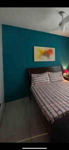 Bett in einem Zimmer mit blauer Wand in der Unterkunft Nosso Repouso Saquarema - Casa inteira com Piscina,churrasqueira privativos, Wi-fi,900m da praia, Tv-Smart. in Saquarema