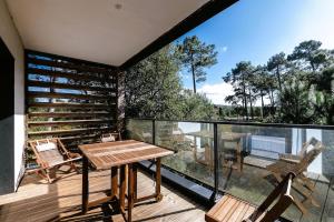 a patio with a wooden table and chairs on a balcony at Villa cork contis 1 in Lit-et-Mixe